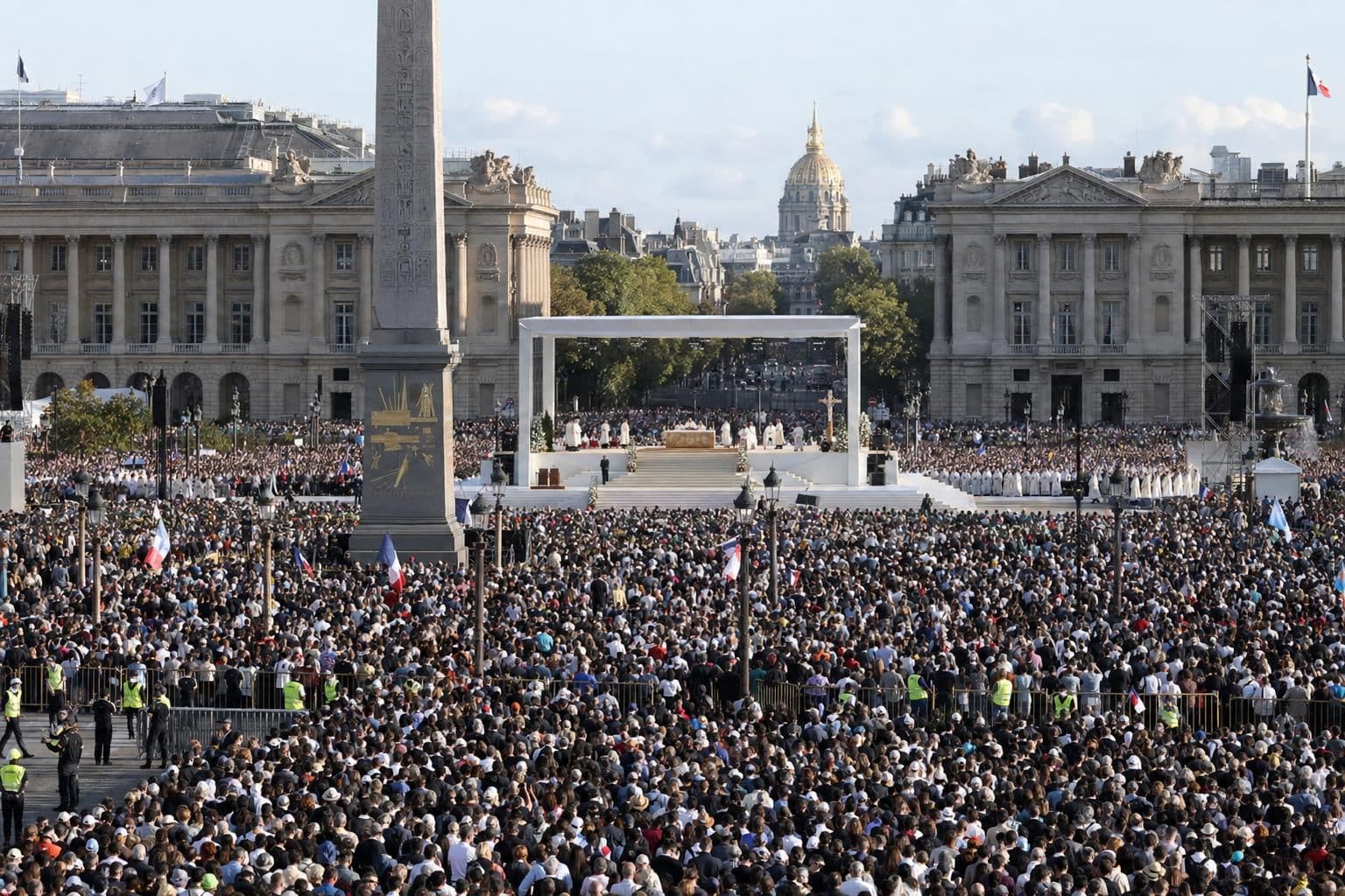 Huge crowd gathered for an outdoor papal Mass in a large Paris square, with an altar stage in the distance