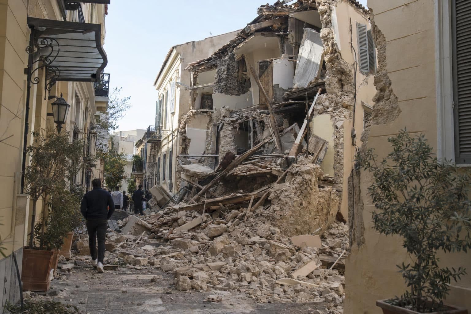 A collapsed residential building and damaged neighboring structures in Athens’ Plaka district.