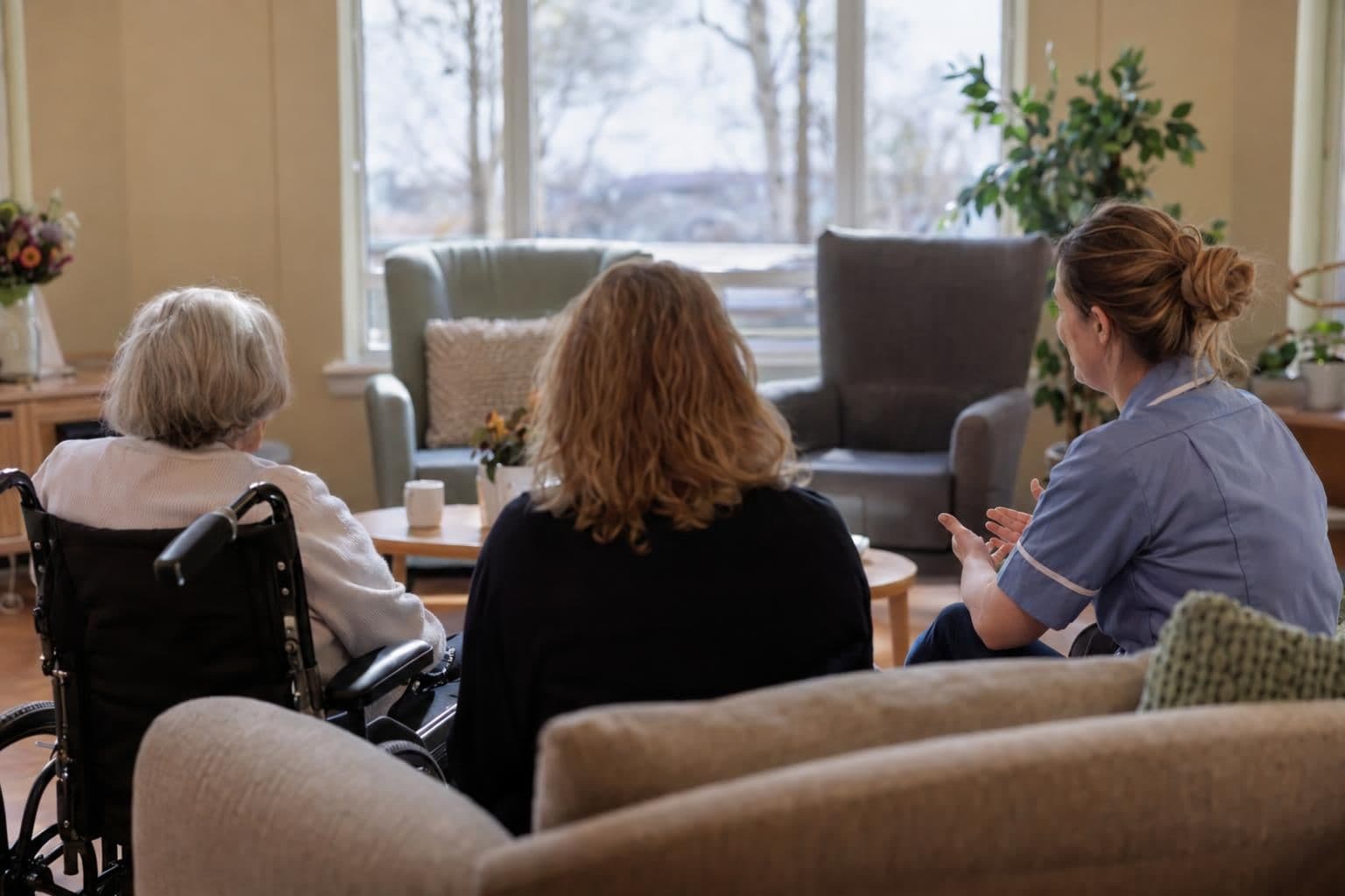 An older resident meets with a relative and care professional in a quiet room.