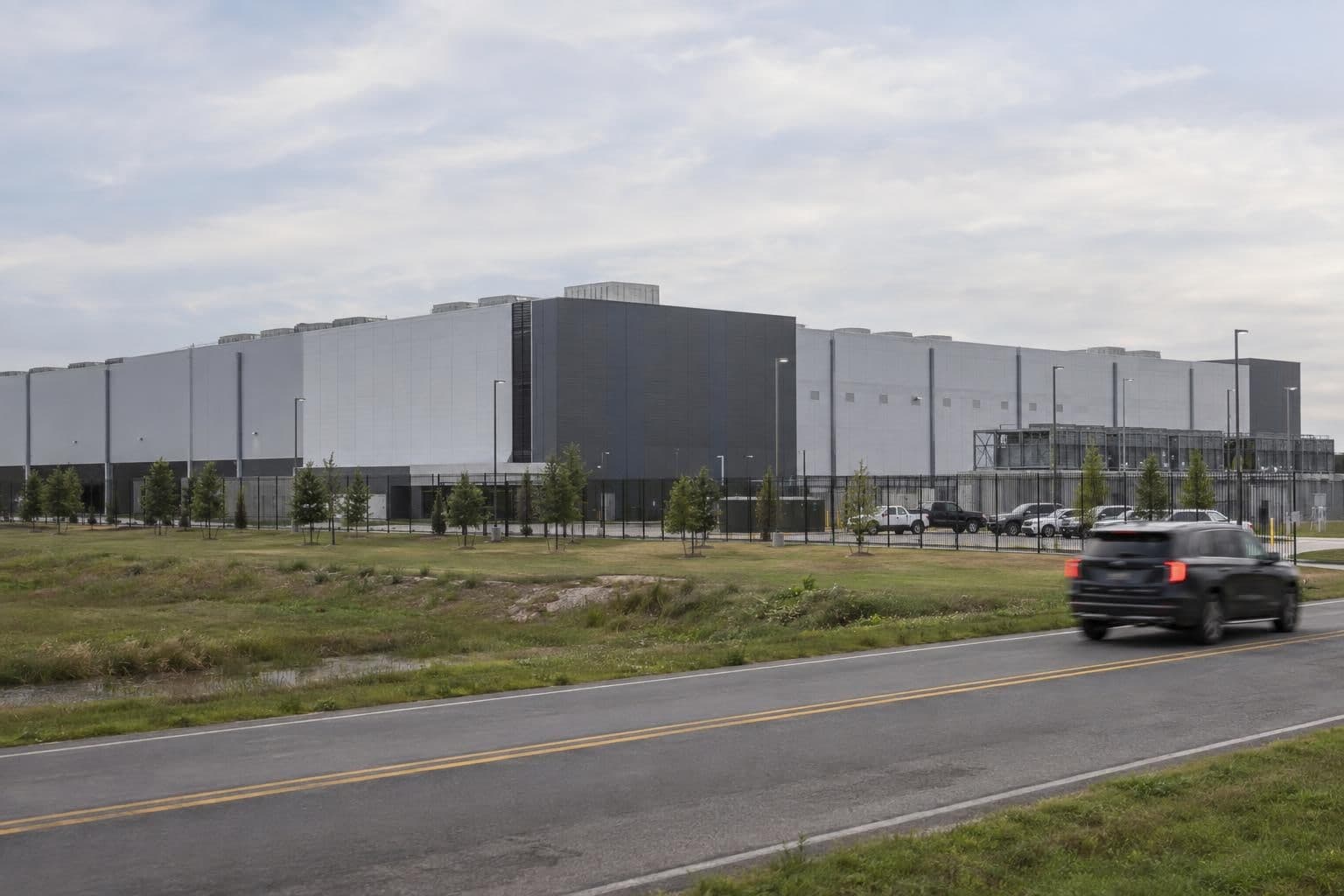 A data-center building seen from outside, with a nearby road and open service area.