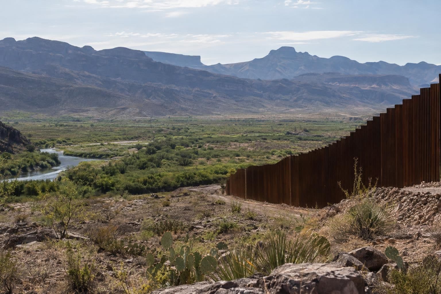 Border wall panels stand in the open, rugged landscape of Texas’ Big Bend region.