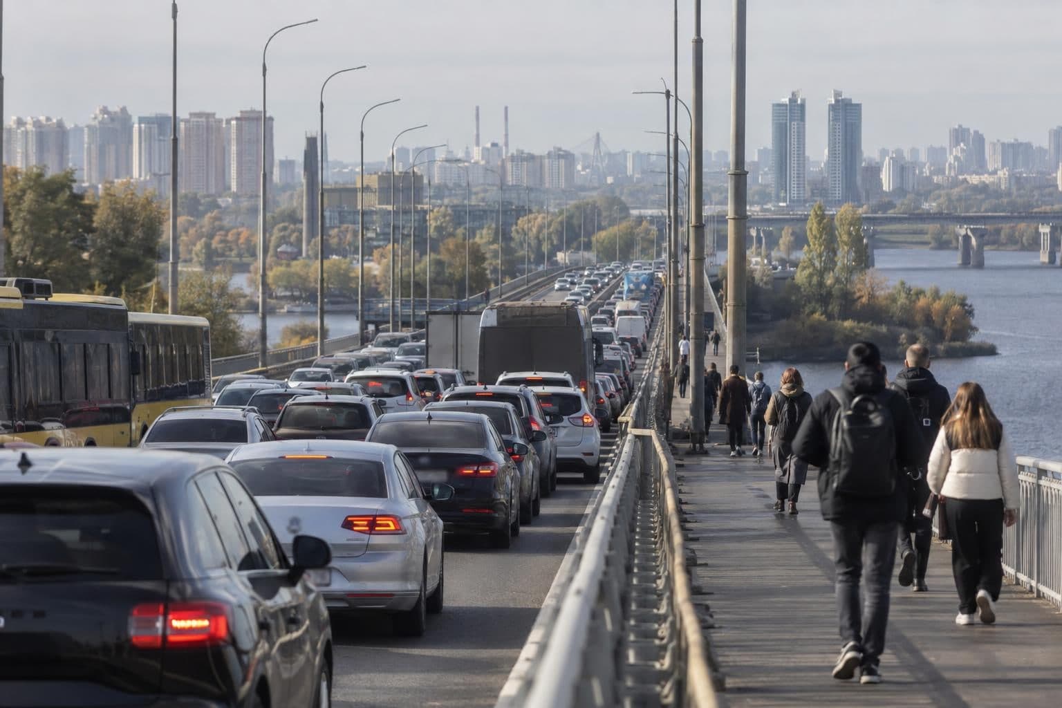Cars and buses queue at a Kyiv river crossing as some commuters continue on foot.