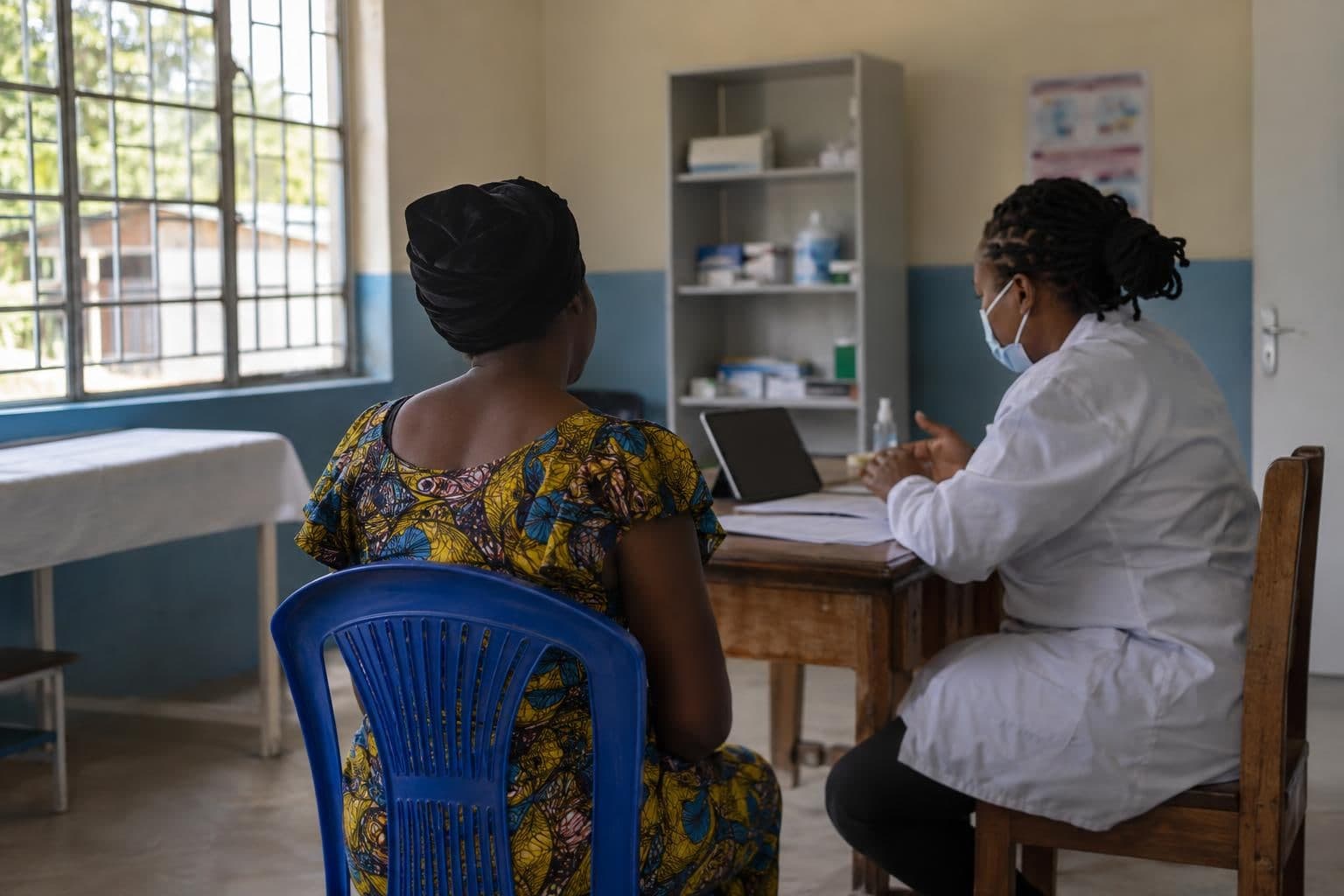 A health worker and trial participant review papers beside an unmarked tablet.