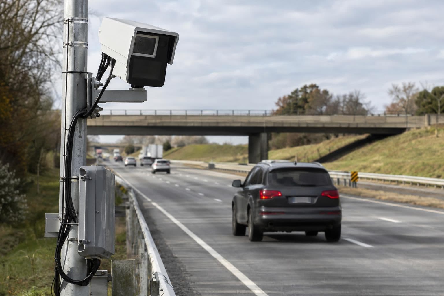 A roadside license-plate reader camera faces a car travelling along a highway.