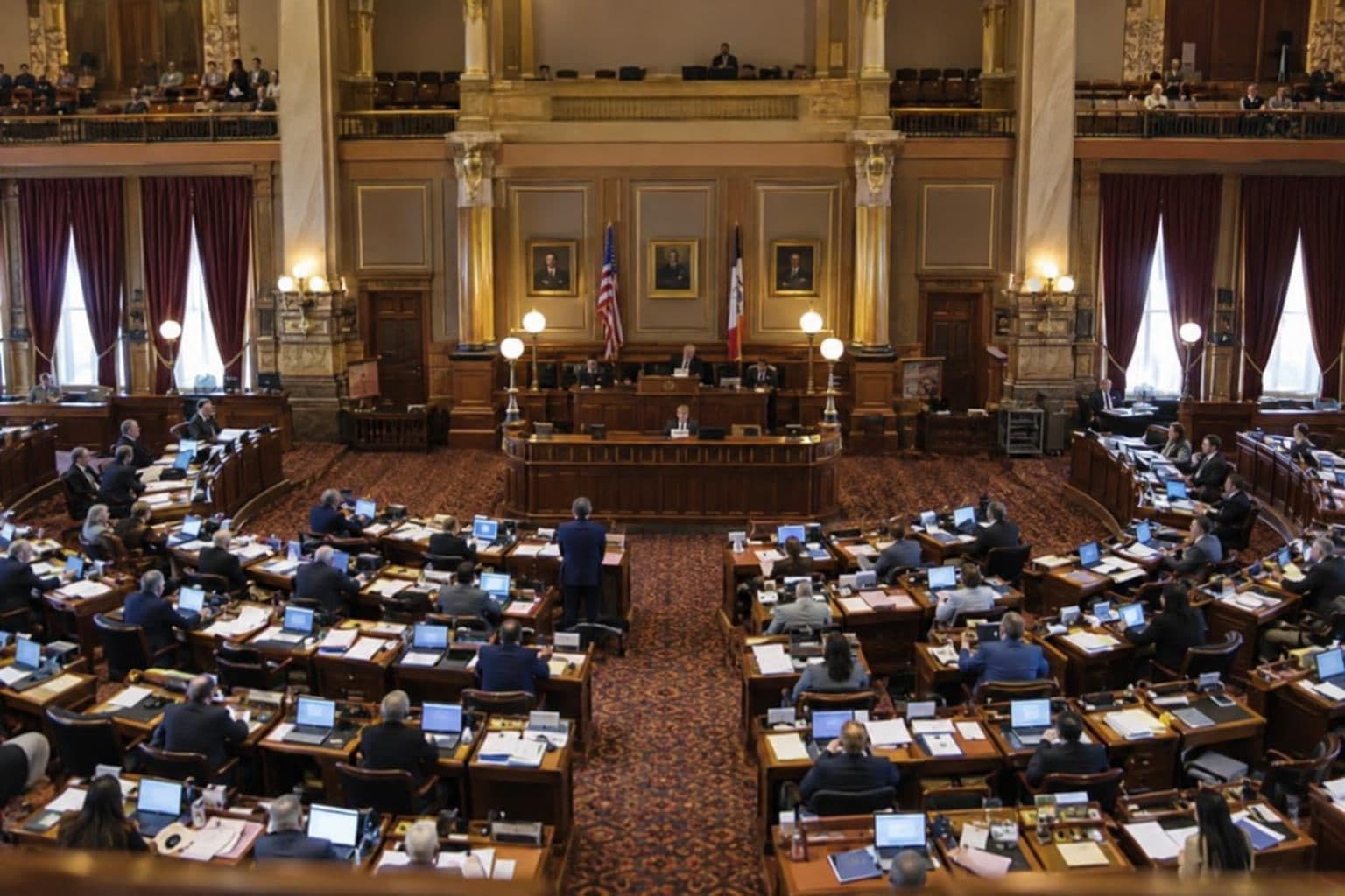 Lawmakers sit at desks in a chamber during consideration of an economic-development bill.