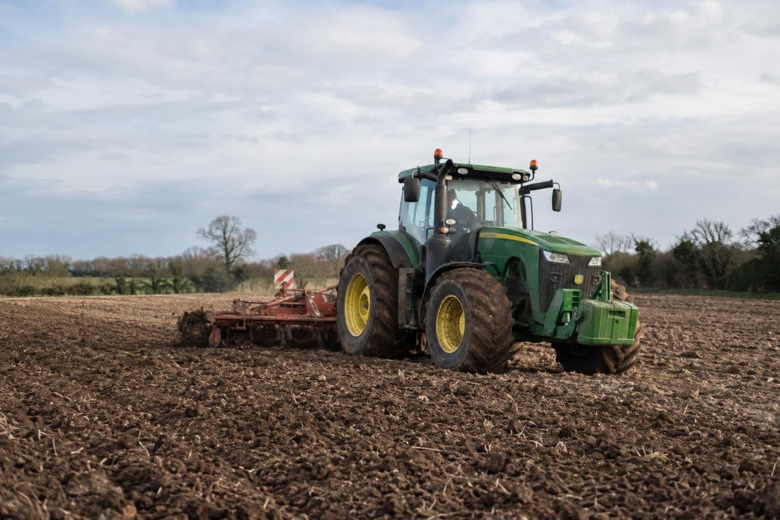 A farm tractor works in a field, illustrating agricultural off-road use.