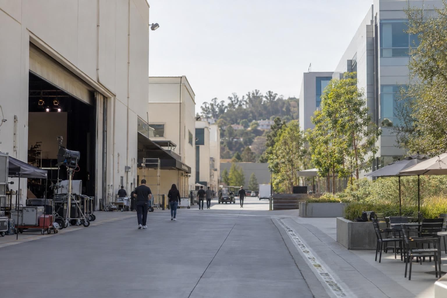 An unbranded film studio and media-office complex with a few people walking outside.