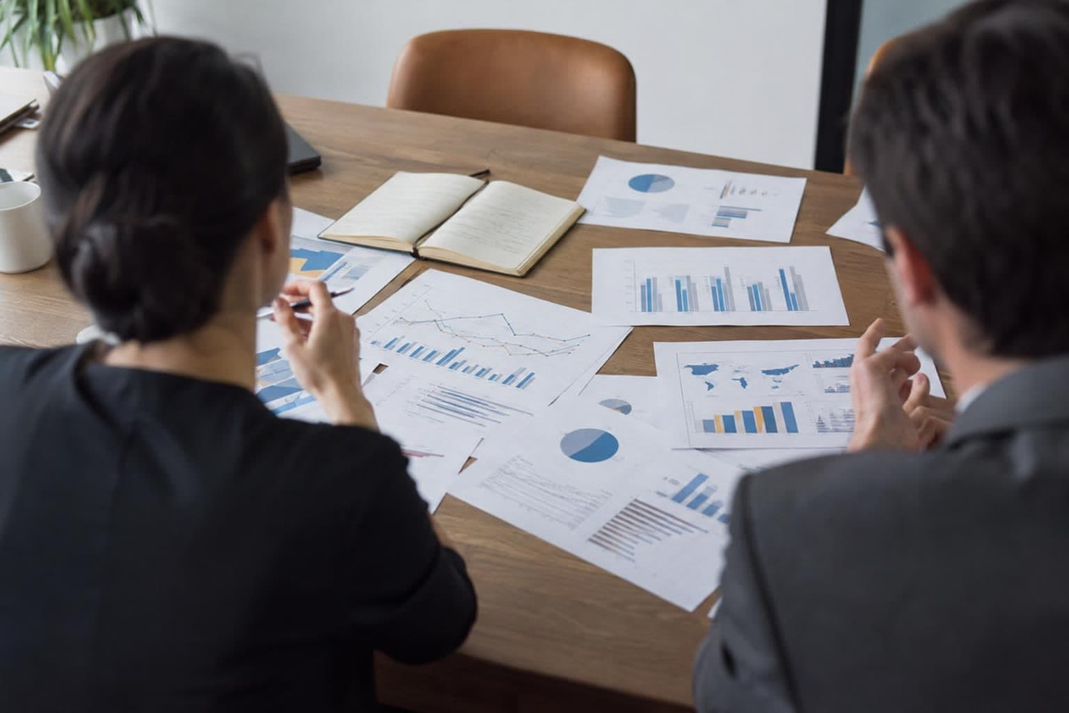 Anonymous figures review economic charts in an office.