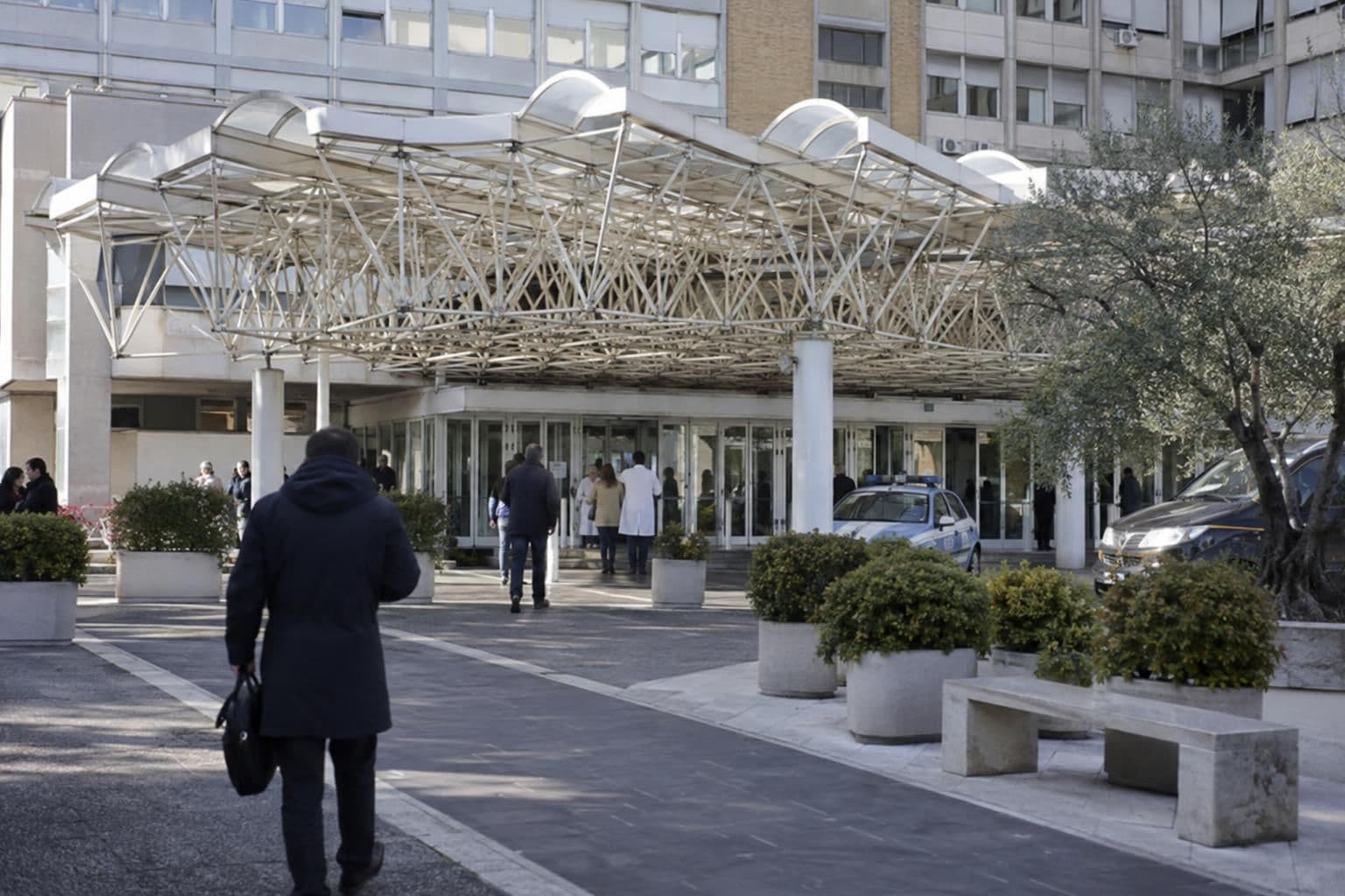 A distant figure arrives at a Rome hospital ahead of a scheduled operation.